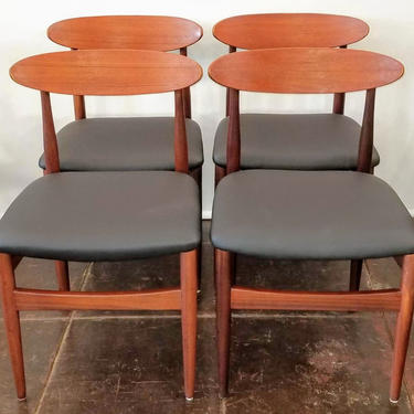 Set of four afrormosia and teak wood dining chairs with black seats.