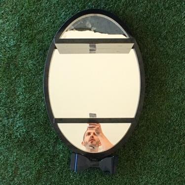 black oval mirror with 2 shelves and bow tie