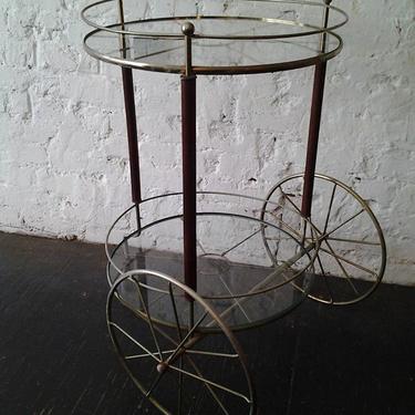 1960s wagon wheel rolling bar cart with walnut trim  accents.  Two-tier cart with thick glass shelving shows off nicely the Mid Century Modern high and low-ball glasses, bottles,