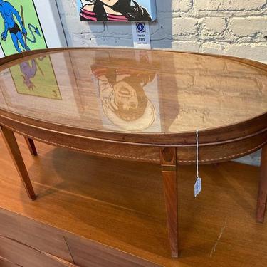 Oval glass topped coffee table with lovely marquetry inlay.  38.25” x 20” x 17.5”