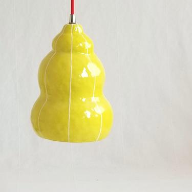 Yellow ceramic pendant light fixture. Red plug in cord 
