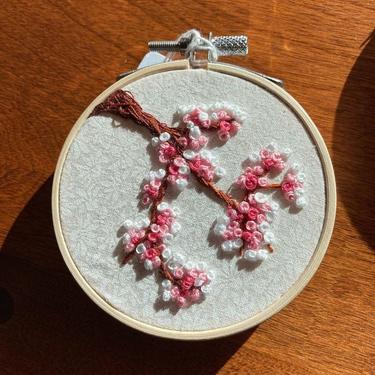 Little embroidered cherry blossom embroidery on patterned fabric. 5.5” hoop 