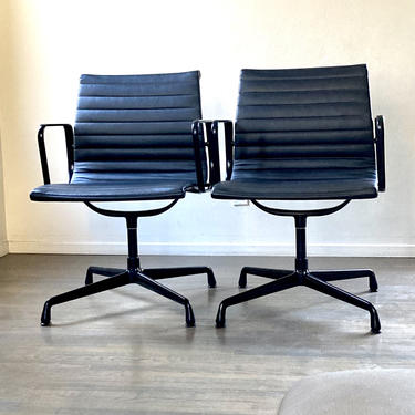 Pair of black leather Eames Aluminum Management chairs in all black 
